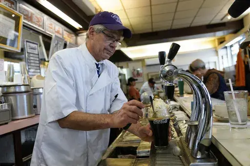 John Philis, a third-generation owner of the Lexington Candy Shop, prepares a Coke float at the luncheonette, Thursday, Sept. 28, 2023, in New York. The old school business met the new world when Nicolas Heller, a TikToker and Instagrammer with 1.2 million followers, popped in for a traditional Coke float. Naturally, he made a video. It went viral, garnering 4.8 million likes. (AP Photo/Mary Altaffer)