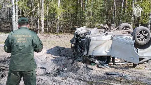 This image taken from video released by the Russian Investigative Committee on Saturday, May 6, 2023, shows a Russian Investigative Committee employee working at the site of the exploded car of Russian writer and publicist Zakhar Prilepin in the region of Nizhny Novgorod, about 400 kilometers (250 miles) east of Moscow. Russian state news agency Tass says the car of Prilepin exploded on Saturday, injuring him and killing his driver. (Russian Investigative Committee via AP)