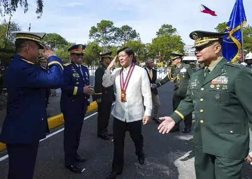 In this photo provided by the Presidential Communications Office, Philippine President Ferdinand Marcos Jr. is greeted during his visit at the Philippine Military Academy in Baguio city, northern Philippines on Saturday Feb. 18, 2023. The Philippine president said Saturday the Chinese coast guard's aiming of a military-grade laser that briefly blinded some crew aboard a Philippine patrol vessel in the disputed South China Sea was not enough for him to invoke a mutual defense treaty with the Unit