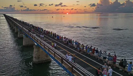 In this aerial photo provided by the Florida Keys News Bureau, attendees watch and toast the sunset at a Florida Keys bicentennial celebration, Friday, May 19, 2023, on the restored Old Seven Mile Bridge in Marathon, Fla. The sunset gathering was among a series of Keys events being staged to mark the 200th anniversary, on July 3, of the Florida Territorial Legislature's 1823 founding of Monroe County, containing the entire island chain. The old bridge was originally part of Henry Flagler's Flori
