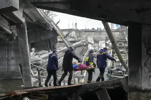 Ukrainian rescue workers carry an elderly woman under the destroyed bridge in Irpin, close to Kyiv close to Kyiv, Ukraine, Friday, April 1, 2022. Talks to stop the fighting in Ukraine resumed Friday, as another attempt to rescue civilians from the shattered and encircled city of Mariupol broke down and Russia accused the Ukrainians of a cross-border helicopter attack on an oil depot. (AP Photo/Efrem Lukatsky)