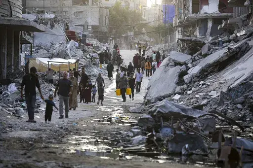 Palestinians displaced by the Israeli air and ground offensive on the Gaza Strip, walk through a dark streak of sewage flowing into the streets of the southern town of Khan Younis, Gaza Strip, on July 4, 2024. Health authorities and aid agencies are racing to avert an outbreak of polio in the Gaza Strip after the virus was detected in the territory's wastewater and three cases with a suspected polio symptom have been reported. (AP Photo/Jehad Alshrafi, File)