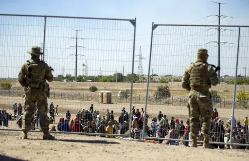 Migrants wait in line adjacent to the border fence under the watch of the Texas National Guard to enter into El Paso, Texas, Wednesday, May 10, 2023. U.S. authorities say an 8-year-old girl died Wednesday, May 17, in Border Patrol custody, a rare occurrence that comes as the agency struggles with overcrowding. The Border Patrol had 28,717 people in custody on May 10, the day before pandemic-related asylum restrictions expired, which was double from two weeks earlier, according to a court filing.
