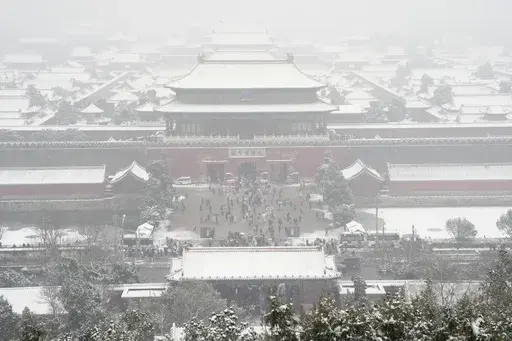 The snow covered Forbidden City is seen from a hilltop pavilion in Beijing, Wednesday, Dec. 13, 2023. Throngs of people in boots and down parkas climbed a hill that overlooks the Forbidden City this week to jostle with others trying to get a shot of the snow-covered roofs of the former imperial palace. (AP Photo/Ng Han Guan)