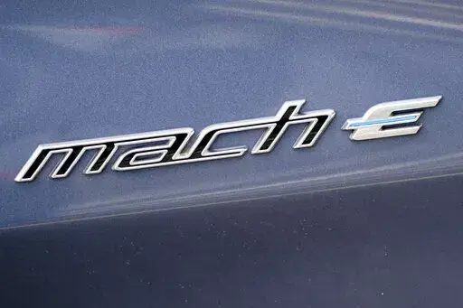 In this photo made on Thursday, May 6, 2021, the badging logo is seen on a 2021 Ford Mustang Mach E at a Ford dealer in Wexford, Pa. Ford is spinning off its electric vehicles and internal combustion businesses into separate units. The automaker said Wednesday, March 2, 2022 that its plan includes two distinct, but strategically interdependent, auto businesses – Ford Blue and Ford Model e.  (AP Photo/Keith Srakocic)