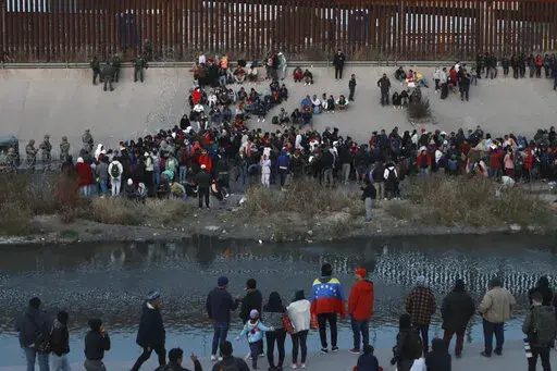 Migrants gather at a crossing into El Paso, Texas, as seen from Ciudad Juarez, Mexico, Tuesday, Dec. 20, 2022. Tensions remained high at the U.S-Mexico border Tuesday amid uncertainty over the future of restrictions on asylum-seekers, with the Biden administration asking the Supreme Court not to lift the limits before Christmas. (AP Photo/Christian Chavez)