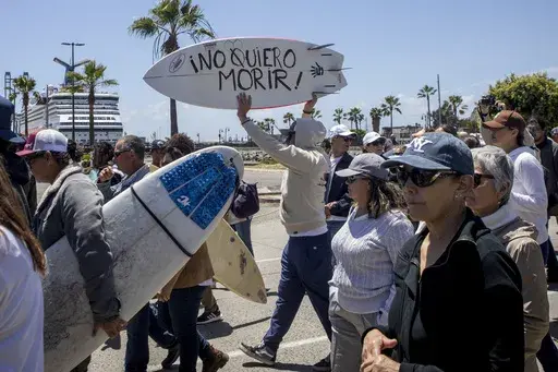 A demonstrator holding a bodyboard written in Spanish " I don't want to die" protests the disappearance of foreign surfers in Ensenada, Mexico, Sunday, May 5, 2024. Mexican authorities said Friday that three bodies were recovered in an area of Baja California near where two Australians and an American went missing last weekend during an apparent camping and surfing trip. (AP Photo/Karen Castaneda)