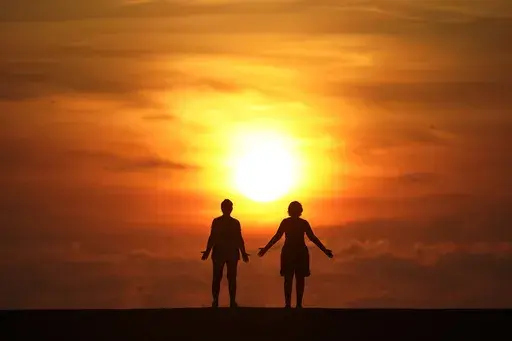 In this Sept. 19, 2020 file photo, a couple stands on a jetty as the sun rises over the Atlantic Ocean in Bal Harbour, Fla. Millions of Americans struggle with mental illnesses. One way to do so is by setting up a trust. An important question to ask is how a trust will affect their loved one’s eligibility for government benefits. Other factors to explore include the best trustees to appoint and whether their estate plan is clear and easy to follow. (AP Photo/Wilfredo Lee, File)
