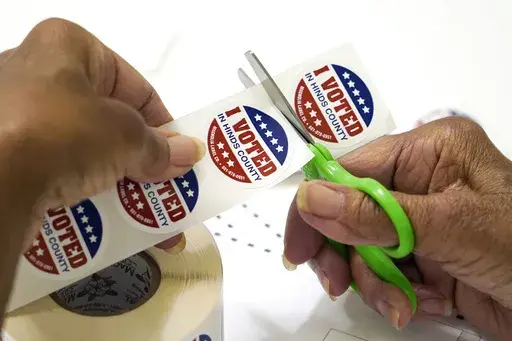 A precinct worker in Jackson, Miss., cuts individual "I Voted in Hinds County" stickers on Aug. 8, 2023. Election officials in Mississippi's most populous county had to scramble to complete required poll worker training after an early September breach involving county computers. (AP Photo/Rogelio V. Solis, File)
