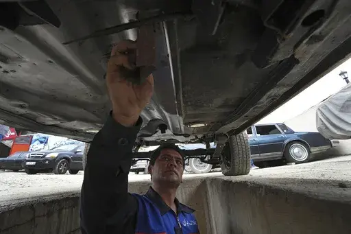 A worker sands an under a restored Cadillac Seville at restorer Khosro Dahaghin's workshop in Roudehen, some 30 miles (45 kilometers) east of downtown Tehran, Iran, Wednesday, June 7, 2023. Dahaghin’s passion for restoring the cars means he carefully examines each frame, component and stitch of the Sevilles in Iran, a challenge that's only grown as parts become scarce, the vehicles get older and as the country faces U.S. sanctions over its nuclear program. (AP Photo/Vahid Salemi)