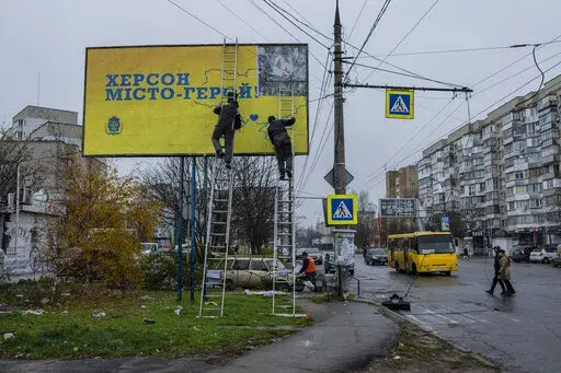 City workers set up a billboard in Kherson, southern Ukraine, Thursday, Nov. 24, 2022. The billboard reads in Ukrainian "Kherson Hero City". (AP Photo/Bernat Armangue)
