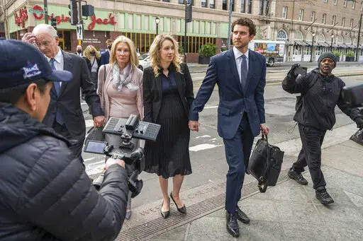 Theranos founder and CEO Elizabeth Holmes, center, walks into federal court in San Jose, Calif., Nov. 18, 2022. Holmes is citing her recently born child as another reason she should be allowed to delay the start of a more than 11-year prison sentence while her lawyers appeal her conviction for duping investors about the capabilities of her failed company's blood-testing technology. The birth of Holmes' second child was confirmed in court documents filed Thursday, Feb. 23, 2023, in advance of a M