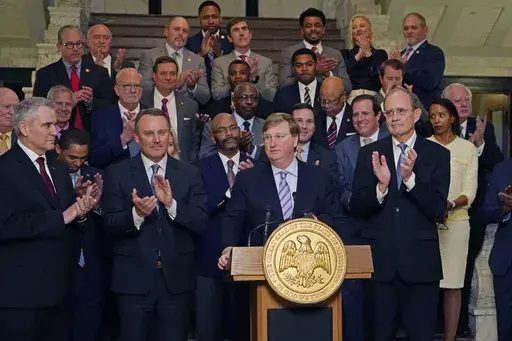 Mississippi Republican Gov. Tate Reeves, center, receives applause from House Speaker Jason White, R-West, left, and Republican Lt. Gov. Delbert Hosemann, right, as well as a bipartisan group of legislators, for pursing a package of state incentives to support a plan by Amazon Web Services to build two data centers in the central part of the state, Thursday, Jan. 25, 2024, during the celebratory announcement at the Mississippi Capitol in Jackson, Miss. (AP Photo/Rogelio V. Solis)