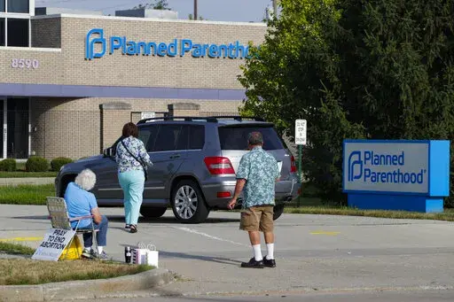 Abortion protesters attempt to hand out literature as they stand in the driveway of a Planned Parenthood clinic in Indianapolis, on Aug. 16, 2019. Almost three months after Roe v. Wade was overturned, the landscape of abortion access is still shifting significantly in some states. Changing restrictions and litigation in neighboring Indiana and Ohio this week illustrate the whiplash for providers and patients navigating sudden changes in what is allowed where. (AP Photo/Michael Conroy, File)