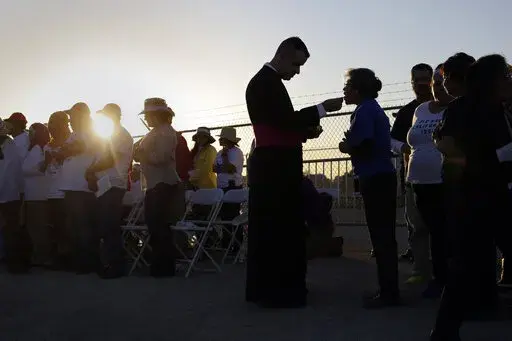 Migrants watching Pope Francis' Mass in Juarez, Mexico, from a levee along the banks of the Rio Grande in El Paso, Texas, take part in Communion, Wednesday, Feb. 17, 2016. According to a poll from The Associated Press-NORC Center for Public Affairs Research conducted in mid-May 2022, only 31% of lay Catholics agree that politicians supporting abortion rights should be denied Communion, while 66% say they be allowed access to the sacrament. (AP Photo/Eric Gay, File)