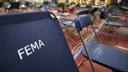 A portable cot, with the Federal Emergency Management Agency logo FEMA printed on the backrest, and other cots line the basketball court at a makeshift medical facility in a gymnasium at Southern New Hampshire University in Manchester, N.H., March 24, 2020. FEMA may have been double-billed for the funerals of hundreds of people who died of COVID-19, the Government Accountability Office said in a new report Wednesday, April 27, 2022. (AP Photo/Charles Krupa, File)