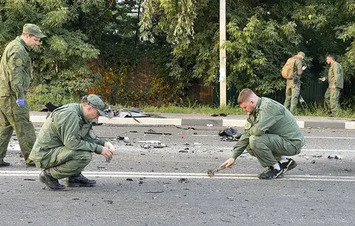 In this handout photo taken from video released by Investigative Committee of Russia on Sunday, Aug. 21, 2022, investigators work on the site of explosion of a car driven by Daria Dugina outside Moscow. Daria Dugina, the daughter of Alexander Dugin, the Russian nationalist ideologist often called "Putin's brain", was killed when her car exploded on the outskirts of Moscow, officials said Sunday. The Investigate Committee branch for the Moscow region said the Saturday night blast was caused by a 