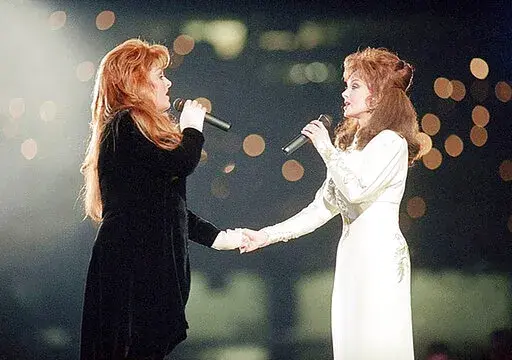 Wynonna Judd, left, and her mother, Naomi Judd, of The Judds, perform during the halftime show at Super Bowl XXVIII in Atlanta on Jan. 30, 1994. Naomi Judd, the Kentucky-born matriarch of the Grammy-winning duo The Judds and mother of Wynonna and Ashley Judd, has died, her family announced Saturday, April 30, 2022. She was 76. (AP Photo/Eric Draper, File)