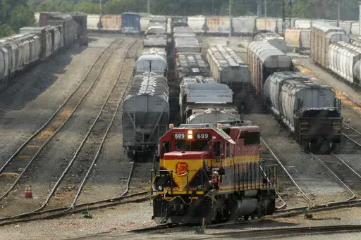 A worker climbs aboard a locomotive at a CPKC rail yard Wednesday, Aug. 21, 2024, in Kansas City, Mo. (AP Photo/Charlie Riedel)