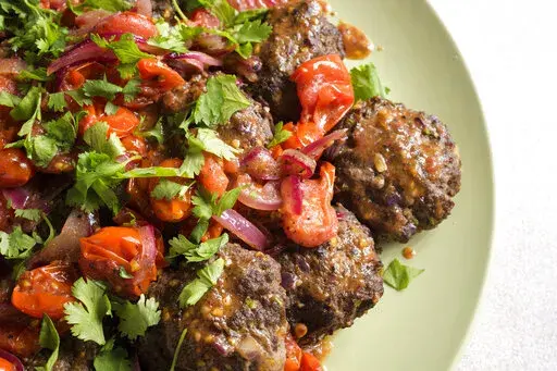 This image released by Milk Street shows a recipe for Spicy Ground Beef Kebabs w/Tomato-Sumac Sauce. (Milk Street via AP)