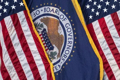 The flag of the Federal Reserve hangs between American flags at a news conference following a Federal Open Market Committee meeting on July 26, 2023 in Washington. On Wednesday, the Federal Reserve releases minutes from the July meeting when it raised its benchmark borrowing rate by another quarter point to 5.4%, the highest level in 22 years. (AP Photo/Nathan Howard, File)