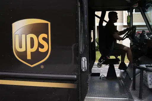 United Parcel Service driver Hudson de Almeida steers through a neighborhood while delivering packages, June 30, 2023, in Haverhill, Mass. The union representing 340,000 UPS workers said Tuesday, Aug. 22, that its members voted to approve the tentative contract agreement reached last month, putting a final seal on contentious labor negotiations that threatened to disrupt package deliveries for millions of businesses and households nationwide. (AP Photo/Charles Krupa, File)