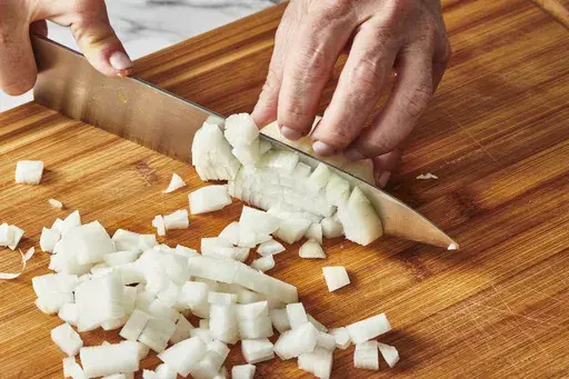 This Oct. 2022 image shows an onion being chopped in New York. There are lots of ways to reduce the amount of wasted food at home. Start by making a meal plan and purchasing just the foods you have plans for. Make a shopping list and avoid impulse buys that might languish in your fridge. (Cheyenne Cohen via AP)