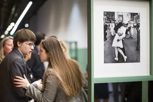 People speak next to a famous photograph taken by Alfred Eisenstaedt of a sailor kissing a nurse in New York's Times Square on V-J Day at the Jewish Museum and Tolerance Center in Moscow on April 14, 2015. Veterans Affairs Secretary Denis McDonough has reversed a department memo shared by a VA undersecretary Tuesday, March 5, 2024, that aimed to ban VA displays of the iconic photograph because it “depicts a non-consensual act” and was inconsistent with the department’s sexual harassment po
