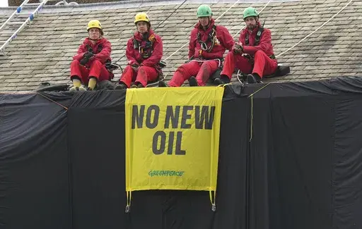 Greenpeace activists sit on the roof of Britain's Prime Minister Rishi Sunak's house in Richmond, North Yorkshire, England, after covering it in black fabric, Thursday Aug. 3, 2023. Greenpeace demonstrators draped the country estate of British Prime Minister Rishi Sunak in black fabric Thursday to protest his plan to expand oil and gas drilling in the North Sea. (Danny Lawson/PA via AP)