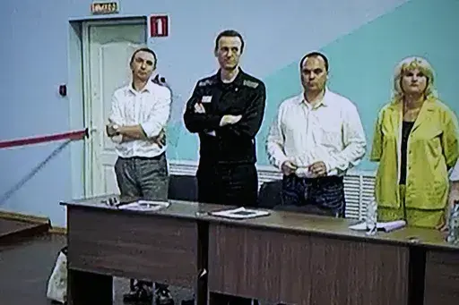 Russian opposition leader Alexei Navalny, 2nd left, is seen on a TV screen standing among his lawyers, as he appears in a video link provided by the Russian Federal Penitentiary Service, during a hearing in the colony, in Melekhovo, Vladimir region, about 260 kilometers (163 miles) northeast of Moscow, Russia, on Friday, Aug. 4, 2023. Navalny on Friday was convicted on extremism charges and sentenced to 19 years in prisons, in the harshest ruling against the imprisoned Kremlin critic to date. (A
