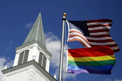 A gay pride rainbow flag flies along with the U.S. flag in front of the Asbury United Methodist Church in Prairie Village, Kan., on April 19, 2019.  The United Methodist Church's Council of Bishops, ending a five-day meeting on Friday, April 29, 2022, acknowledged the inevitable breakup of their denomination, which will gain momentum during the weekend with the launch of a global movement led by theologically conservative Methodists.  (AP Photo/Charlie Riedel, File)