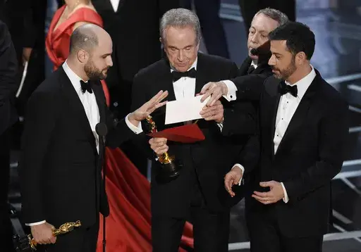 "La La Land" producer Jordan Horowitz, left, presenter Warren Beatty, center, and host Jimmy Kimmel right, look at an envelope announcing "Moonlight" as best picture at the Oscars on Sunday, Feb. 26, 2017, in Los Angeles. It was originally announced mistakenly that "La La Land" was the winner. (Photo by Chris Pizzello/Invision/AP, File)