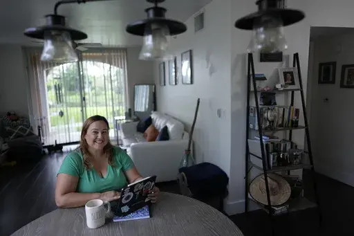 Melissa Lombana, 43, a high school teacher and mountain bike enthusiast, poses for a picture while working online, in her one-bedroom apartment in Miramar, Fla., Wednesday, July 26, 2023. Lombana's rent has increased each of the last two years and now amounts to nearly half her monthly income. "In a year, I will not be able to afford living here at all," she said. (AP Photo/Rebecca Blackwell)