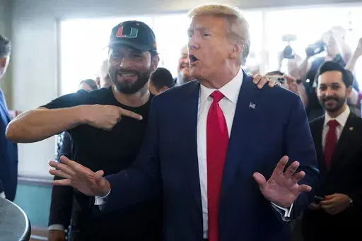 ADDS NAME OF PERSON AT LEFT - Former UFC fighter Jorge Masvidal gestures towards former President Donald Trump as he visits Versailles restaurant on Tuesday, June 13, 2023, in Miami. Trump appeared in federal court Tuesday on dozens of felony charges accusing him of illegally hoarding classified documents and thwarting the Justice Department's efforts to get the records back. (AP Photo/Alex Brandon)
