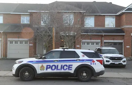 Police cars are parked at the scene where six people were found dead in the Barrhaven suburb of Ottawa on Thursday, March 7, 2024. (Patrick Doyle /The Canadian Press via AP)