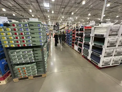 Shoppers make their ways down an aisle lined with clothing and shoes in a Costco warehouse Thursday, Jan. 23, 2025, in Sheridan, Colo. (AP Photo/David Zalubowski, File)