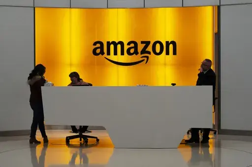 In this Feb. 14, 2019, file photo people stand in the lobby for Amazon offices in New York. Amazon is kicking off its annual security-focused cloud computing conference on Tuesday amid a slowdown in its profitable cloud business Amazon Web Services, or AWS. (AP Photo/Mark Lennihan, File)