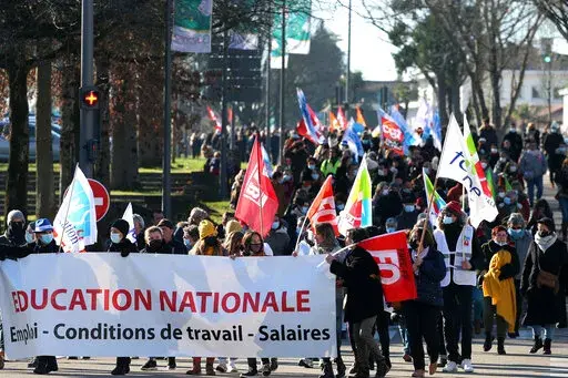 Teachers and students hold a banner reading " National Education- working condition - wages " as they demonstrate in Bayonne, southwestern France, Thursday, Jan. 13, 2022. French teachers have walked out in a nationwide strike Thursday to express anger at the way the government is handling the virus situation in schools, denouncing confusing rules and calling for more protection. (AP Photo/Bob Edme)