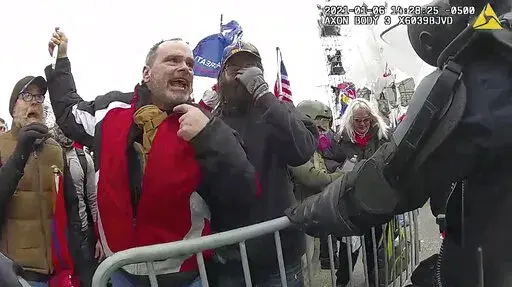 This still frame from Metropolitan Police Department body worn camera video shows Thomas Webster, in red jacket, at a barricade line at on the west front of the U.S. Capitol on Jan. 6, 2021, in Washington. More than 800 people across the U.S. have been charged in the Jan. 6 riot at the Capitol that left officers bloodied and sent lawmakers running in fear, and federal authorities continue to make new arrests practically every week (Metropolitan Police Department via AP)