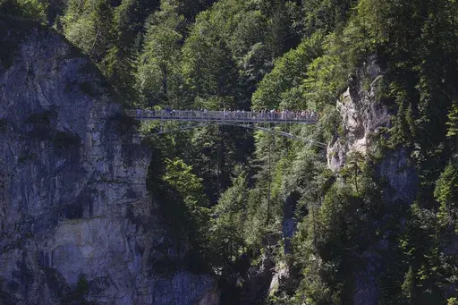 Tourists stand on the Marienbr'cke bridge, near the Neuschwanstein castle, in Schwangau, Germany, Thursday, June 15, 2023. Authorities say an American man has been arrested in Germany after allegedly assaulting two tourists he met near Neuschwanstein castle. The attack, which occurred on Wednesday, left one of the women dead. Police said Thursday that the 30-year-old man met the two women on a hiking path and lured them onto a trail. They said the man then “physically attacked” the younger w