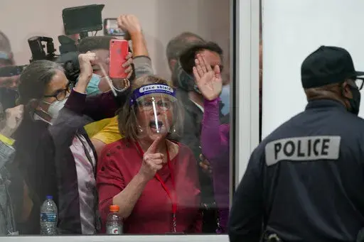 Election challengers yell as they look through the windows of the central counting board as police were helping to keep additional challengers from entering due to overcrowding, in Detroit, Nov. 4, 2020. (AP Photo/Carlos Osorio, File)