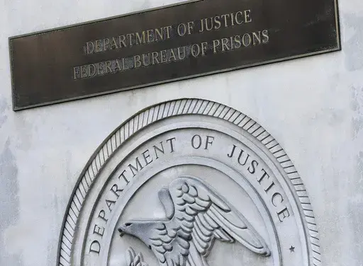 A sign for the Department of Justice Federal Bureau of Prisons is displayed in the Brooklyn borough of New York, July 6, 2020. (AP Photo/Mark Lennihan, File)