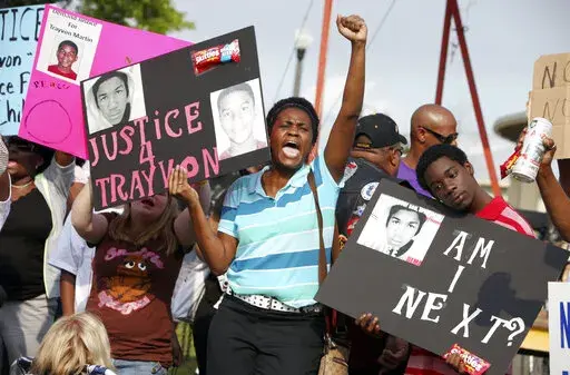 In this March 22, 2012 file photo, protestors, Lakesha Hall, of Sanford, center, and her son, Calvin Simms, right, participate in a rally for Trayvon Martin, the black teenager who was fatally shot by George Zimmerman, a neighborhood watch captain in Sanford, Fla. The killing of Trayvon Martin at the hands of a stranger still reverberates 10 years later -- in protest, in partisanship, in racial reckoning and reactionary response, in social justice and social media. (AP Photo/Julie Fletcher, File