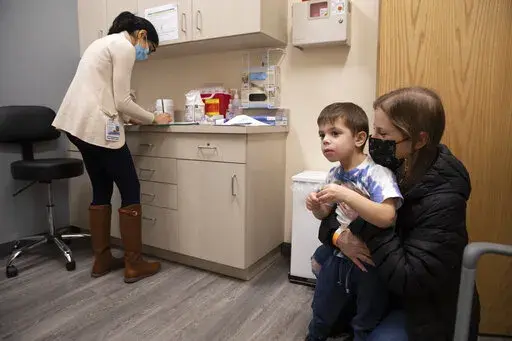Ilana Diener holds her son, Hudson, 3, during an appointment for a Moderna COVID-19 vaccine trial in Commack, N.Y. on Nov. 30, 2021. On Wednesday, March 23, 2022, Moderna said its COVID-19 vaccine works in babies, toddlers and preschoolers, and if regulators agree it could mean a chance to finally start vaccinating the littlest kids by summer. (AP Photo/Emma H. Tobin)