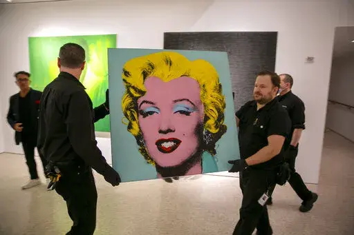 The 1964 painting Shot Sage Blue Marilyn by Andy Warhol is carried in Christie's showroom in New York City on Sunday, May 8, 2022. The auction house predicts it will sell for $200 million on Monday, becoming the most expensive 20th-century artwork to sell at auction. (AP Photo/Ted Shaffrey)