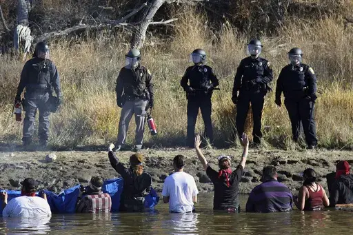 Protestors demonstrating against the expansion of the Dakota Access Pipeline wade in cold creek waters confronting local police, near Cannon Ball, N.D., Nov. 2, 2016. (AP Photo/John L. Mone, File)