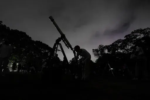 A girl looks at the moon through a telescope in Caracas, Venezuela, on Sunday, May 15, 2022. The best day to spot five planets, Mercury, Jupiter, Venus, Uranus and Mars, lined up in the night sky is Tuesday, March 28, 2023, right after sunset. The five-planet array will be visible from anywhere on Earth, as long as you have clear skies. (AP Photo/Matias Delacroix)