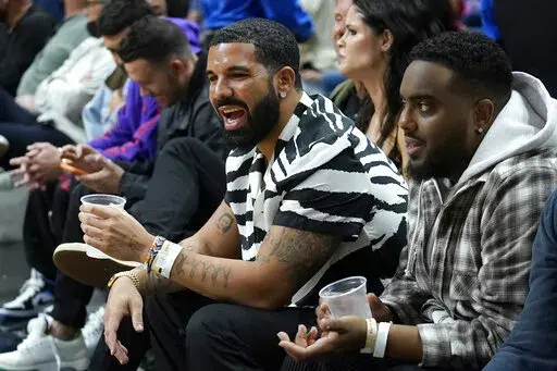 The rapper Drake, front left, looks on during the second half of an NBA basketball game between the Miami Heat and the Atlanta Hawks, Friday, Jan. 14, 2022, in Miami. (AP Photo/Lynne Sladky)