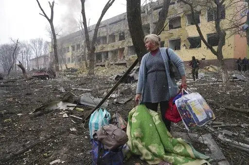 A woman walks outside a maternity hospital that was damaged by shelling in Mariupol, Ukraine, Wednesday, March 9, 2022. (AP Photo/Evgeniy Maloletka, File)