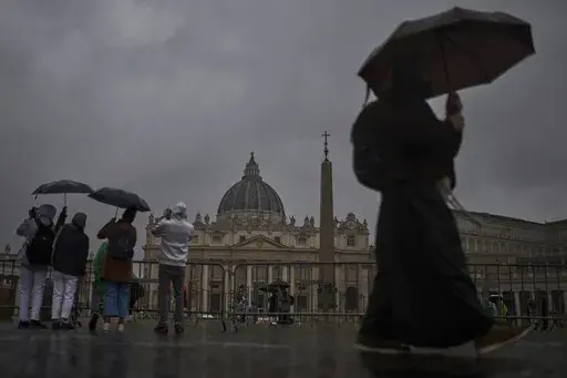 Tourists and locals walk along St. Peter's Square on a rainy day at the Vatican, Wednesday, March 12, 2025. (AP Photo/Francisco Seco)